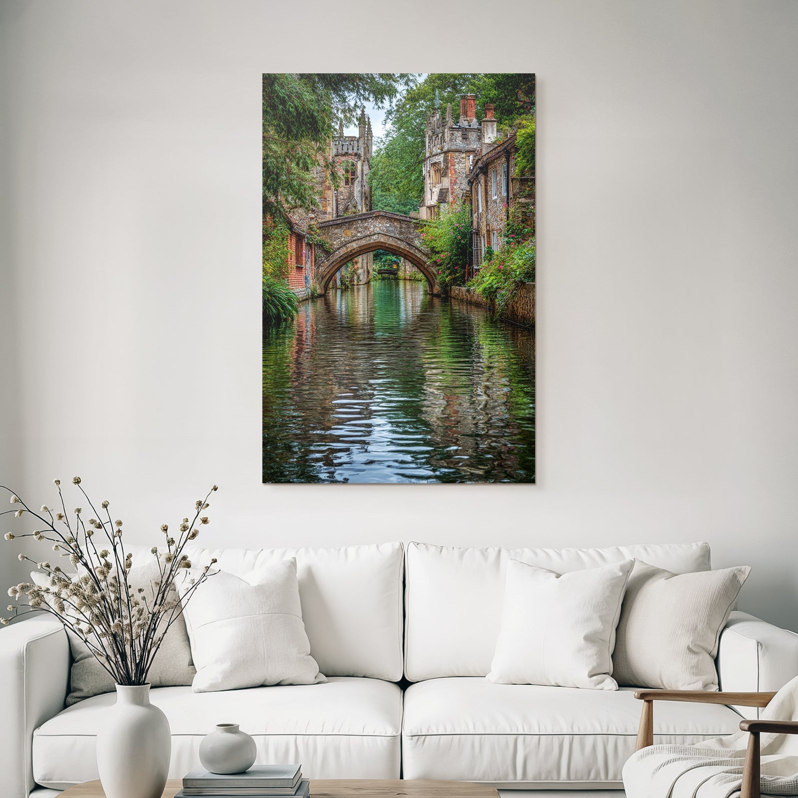 Stone bridge over a tranquil watercourse with green banks and historic buildings