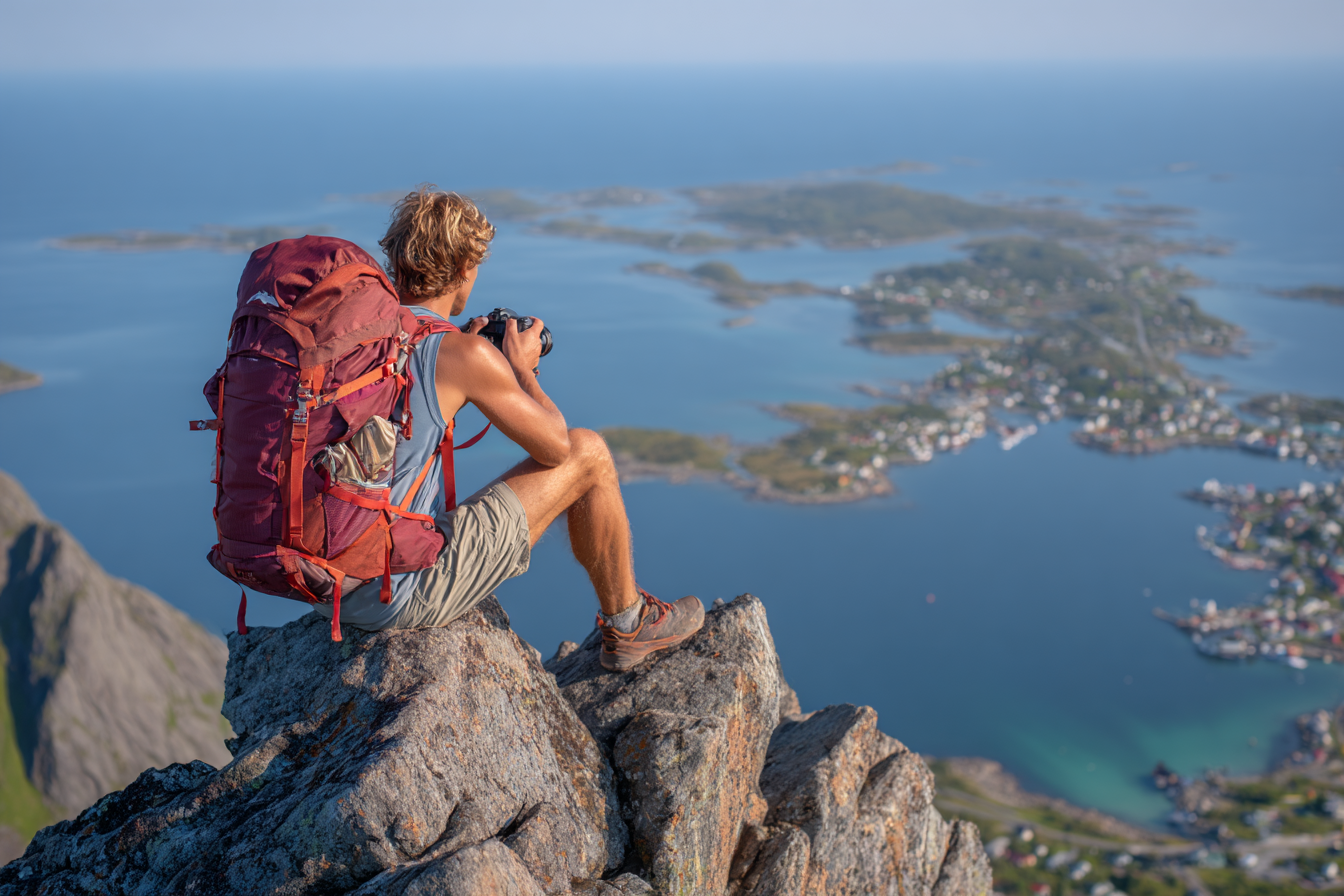Person Mit Kamera Auf Fels Vor Küstenlandschaft Mit Insel Und Dorf | Reisen und Outdoor | Themen und Hobbys