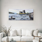 Castle on rock by the sea with bridge and mountains in the background