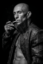 Muscular Bald Man Textured Jacket Smoking Cigarette Intense Black White Photo | Mode und Stil | Menschen und Emotionen