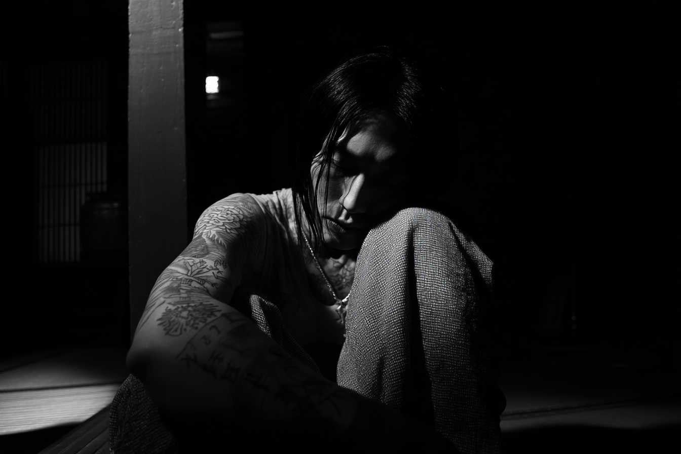 Nachdenkliche Person In Dunkler Umgebung Mit Tattoos | Mode und Stil | Menschen und Emotionen