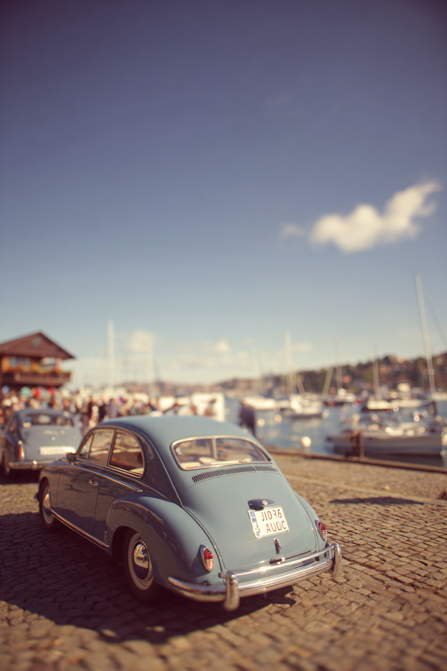 Blaü Auto Am Hafen Mit Boote Auf Dem Wasser Und Leuten Unter Blaüm Himmel | Oldtimer | Mobilitaet und Technik