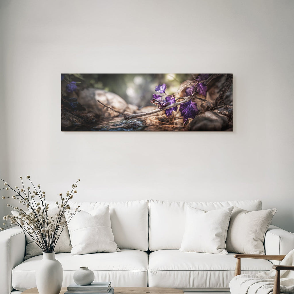 Frog on a branch surrounded by bright purple leaves with a background of water and stones